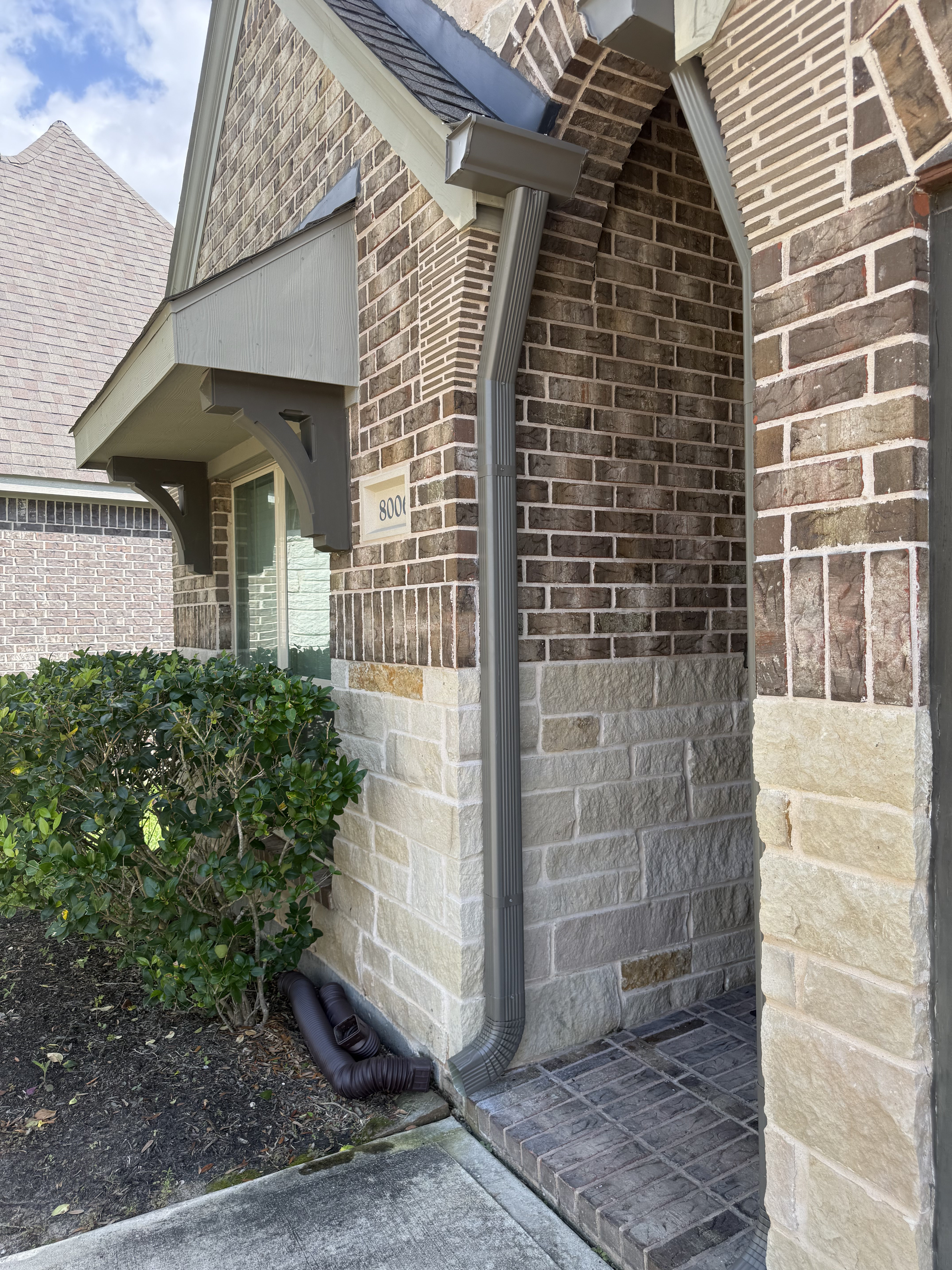 Gutter downspout on stone arch home entrance