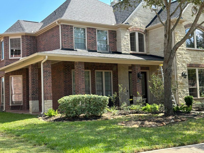 Two-story brick home in the Missouri City area with new seamless gutters installed by Mo City Gutters